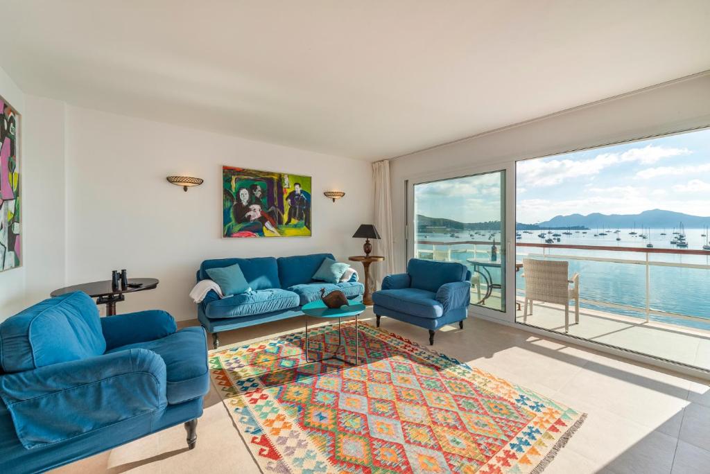 a living room with blue furniture and a large window at Windsong in Port de Pollensa