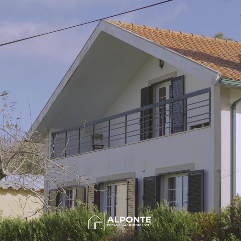 a white house with black shutters and a balcony at Casa da Melanie in Caminha