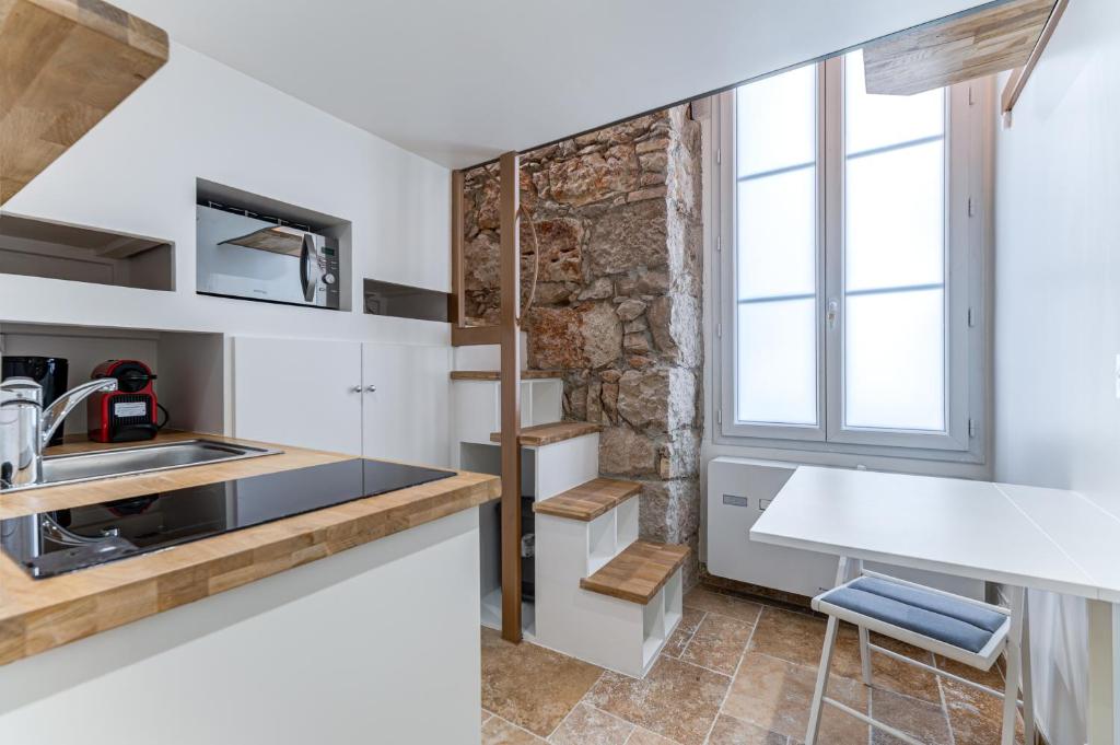 une cuisine avec des armoires blanches et une fenêtre dans l'établissement Place Du Pin - Wifi, AC, 2 pers, à Nice
