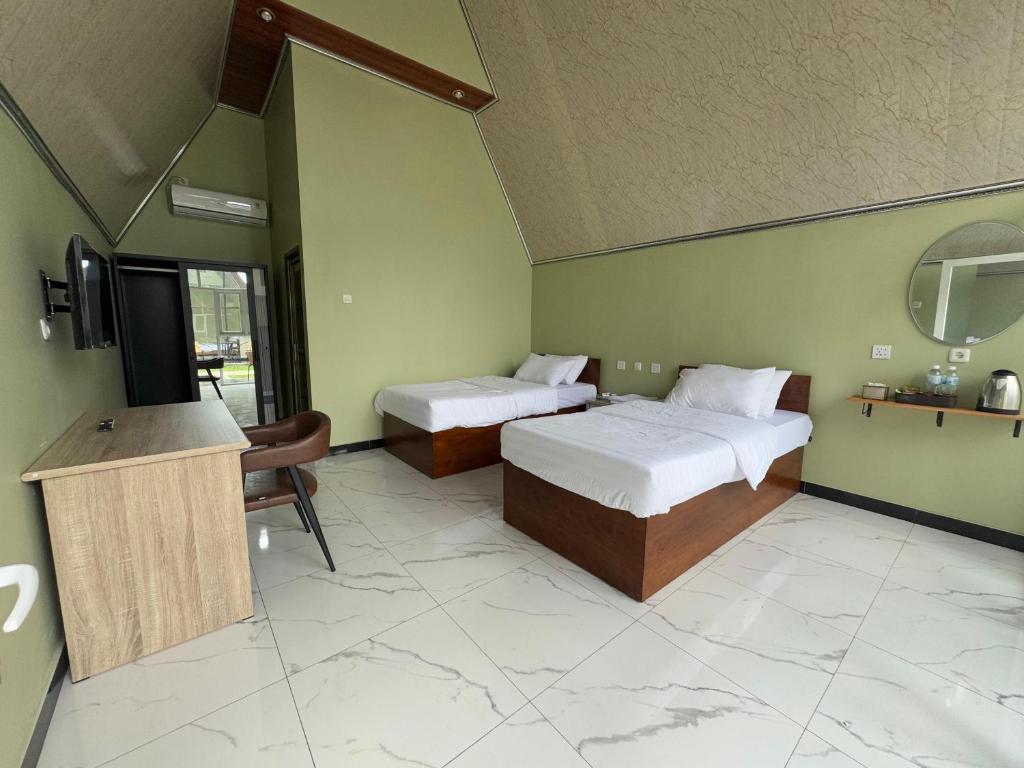 a hotel room with two beds and a television at Kaliningrat Cottage 2 in Pronojiwo