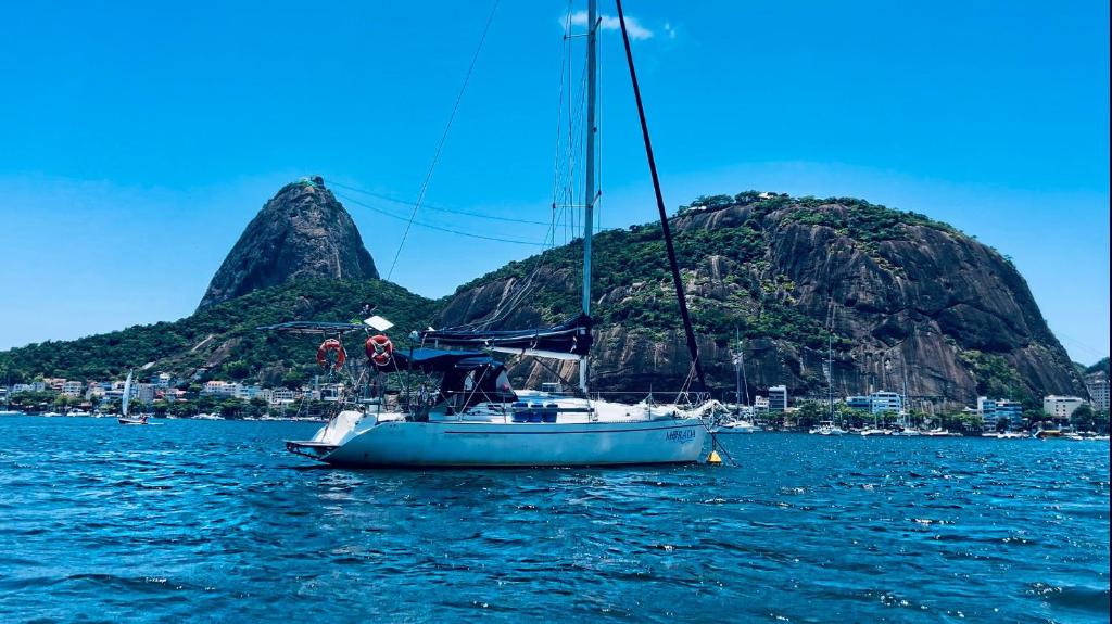 un voilier dans l'eau avec une montagne en arrière-plan dans l'établissement Veleiro Morada - charters and sailing experiences, à Angra dos Reis