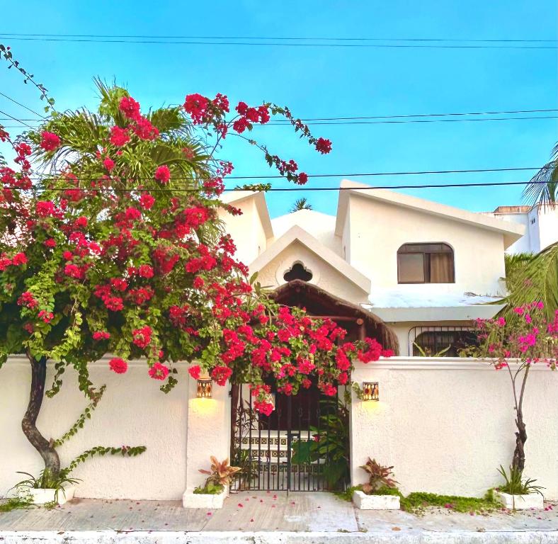 une maison blanche avec des fleurs roses sur une clôture dans l'établissement Casa La Buena Vida 2 bedroom Villa, à Puerto Morelos