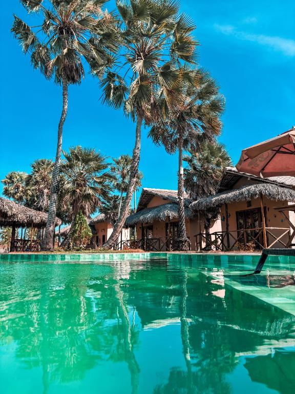a swimming pool with palm trees in the background at Pousada Vila Tapera in Barra Grande