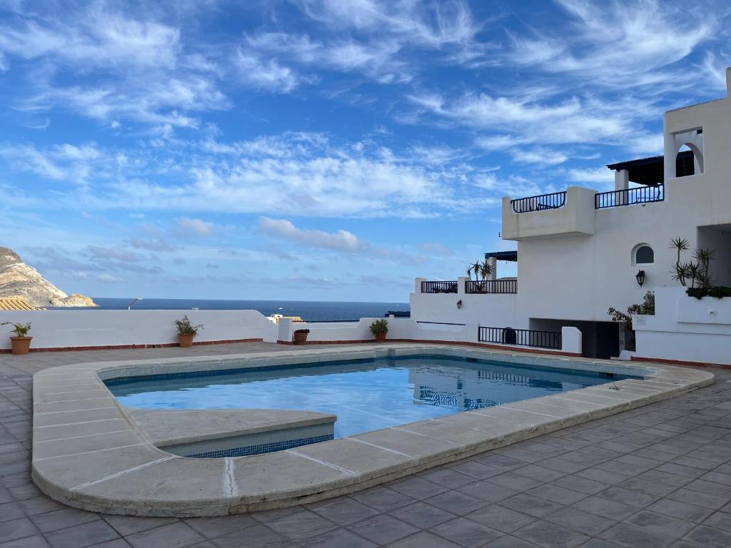 una piscina frente a un edificio con el océano en Casa Bahía Azul, en San José