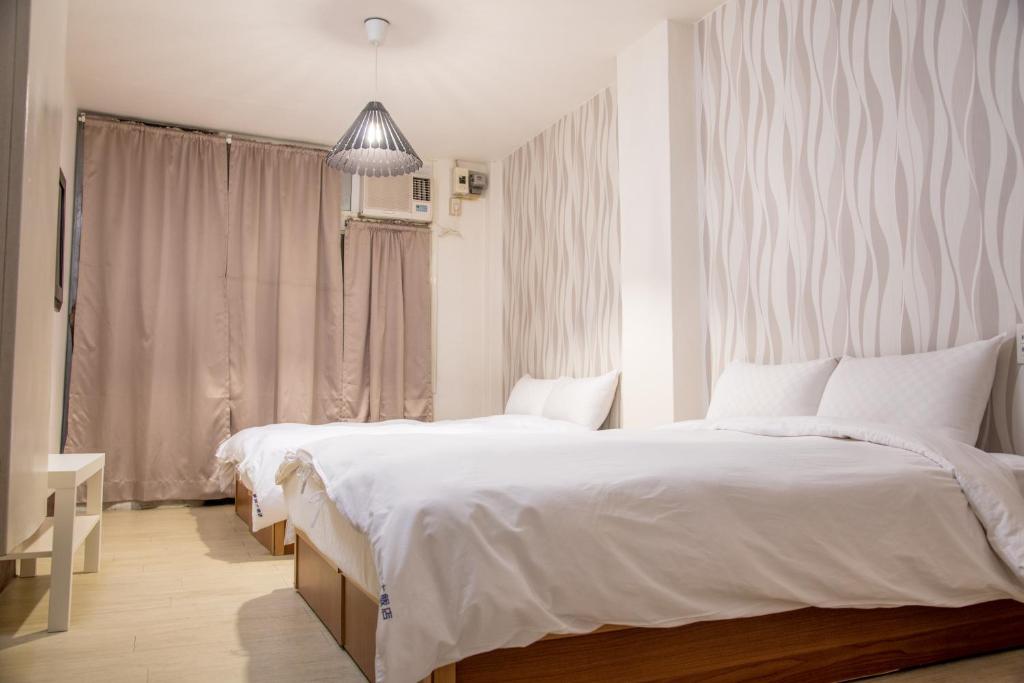 a bedroom with two beds and a large window at Haogong Hotel in Taichung