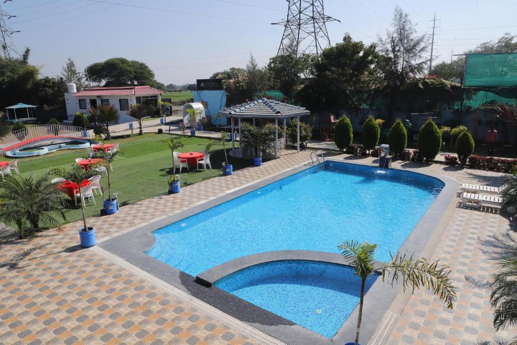 a large swimming pool in a yard with a resort at Cosmos Resort Maliblu in Indore