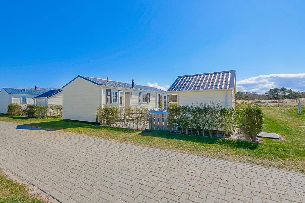 a house with a fence in front of it at Chalet Luttikduin Nr 22 - Callantsoog aan Zee in Callantsoog