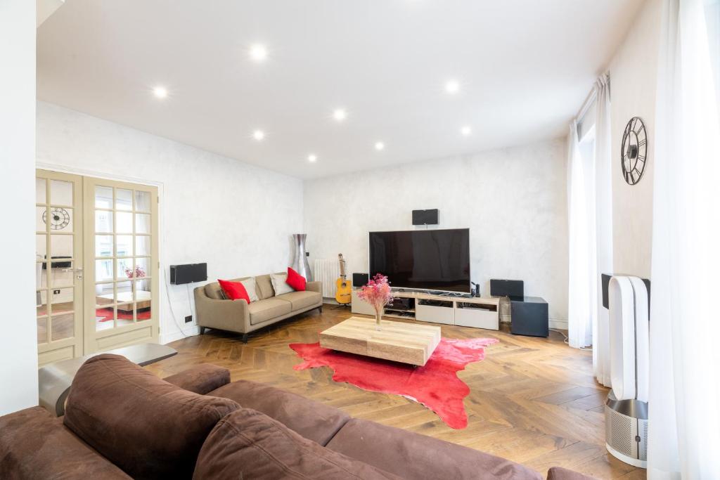 un salon avec un canapé et une télévision dans l'établissement PARIS PASSY Spacieux 2 Chambres Balcon, à Paris