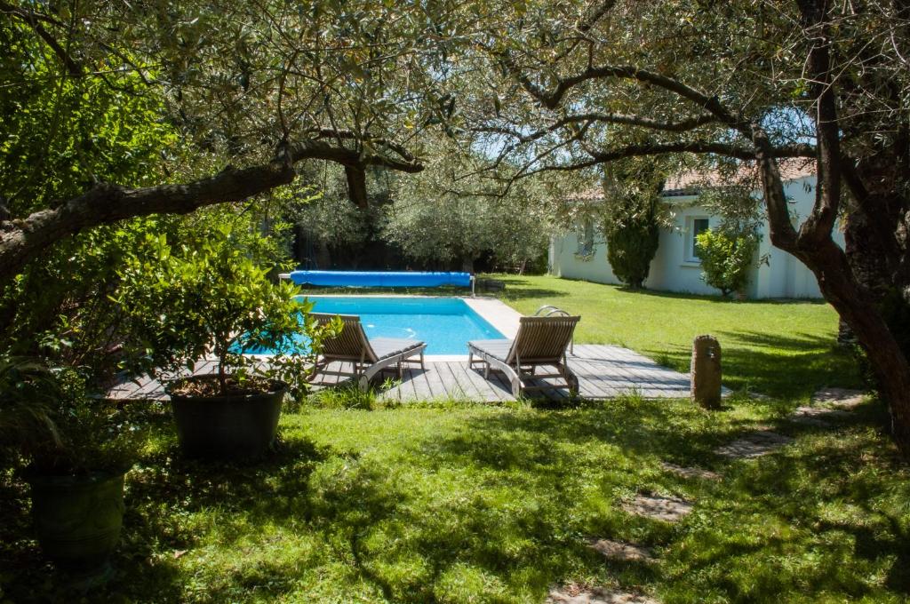une cour arrière avec une piscine et deux chaises dans l'établissement Villa entre Mer et Cévennes, à Villetelle
