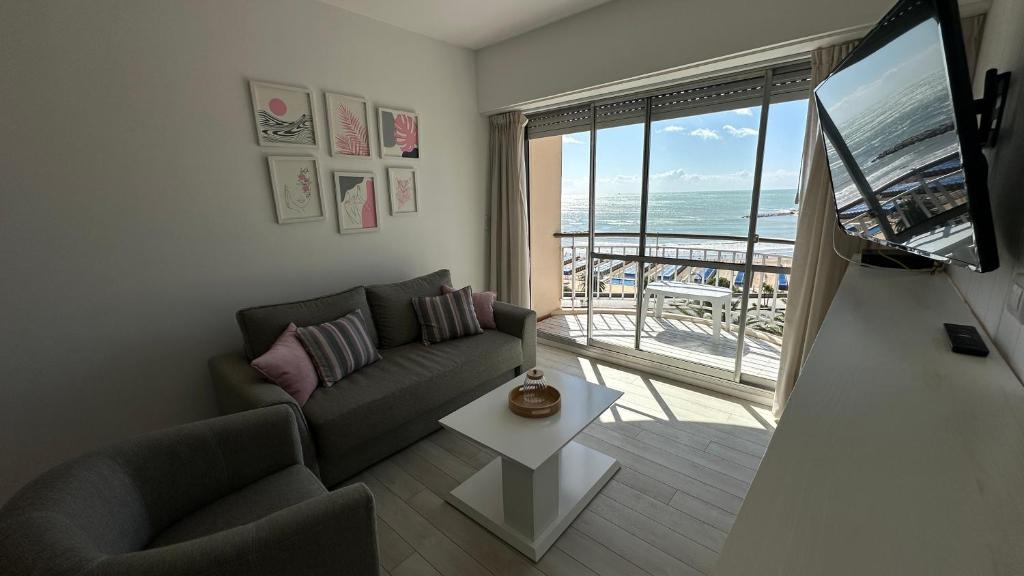 a living room with a couch and a large window at Depto Varese - Depto Vista al Mar Zona Varese Para 3 PAX Con Cochera - Hola Sur in Mar del Plata