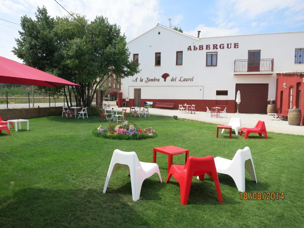un gruppo di sedie sedute sull'erba di fronte a un edificio di Hostal A La Sombra Del Laurel a Navarrete