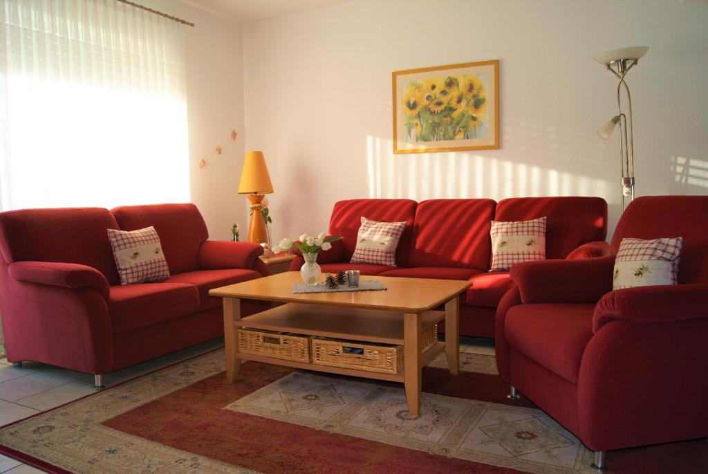 a living room with red couches and a coffee table at Ferienhaus Veldhoen in Norddeich