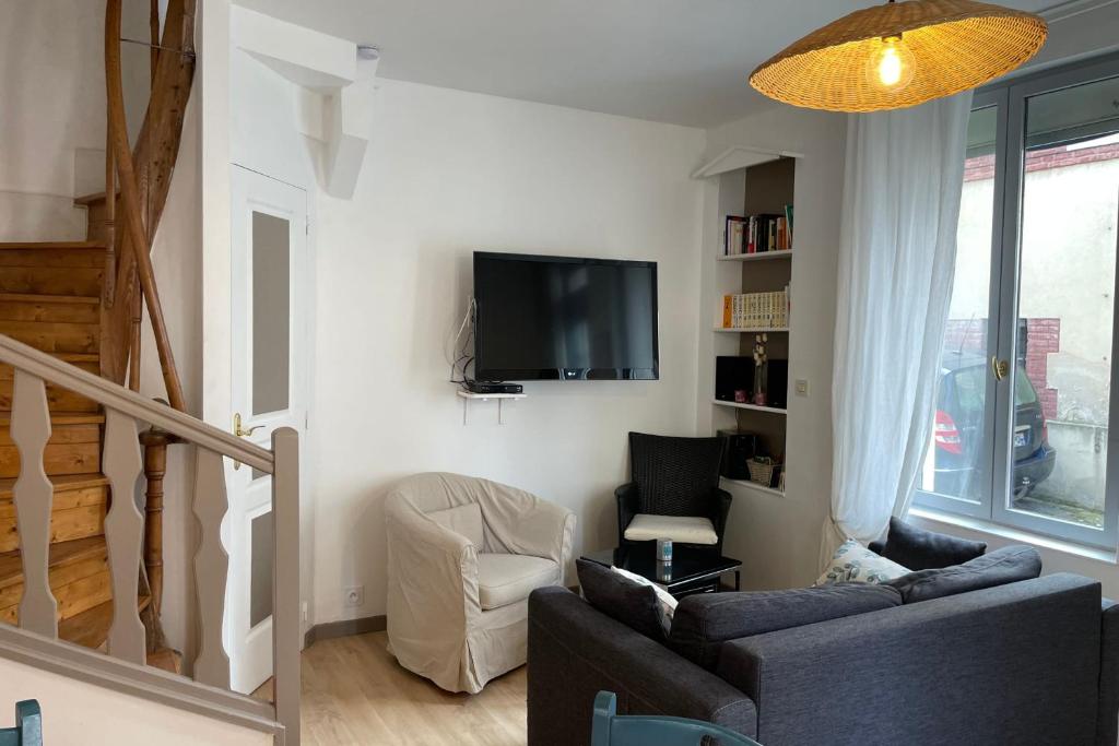 un salon avec un canapé et une télévision sur un mur dans l'établissement Charming fisherman's cottage near the station, à Trouville-sur-Mer