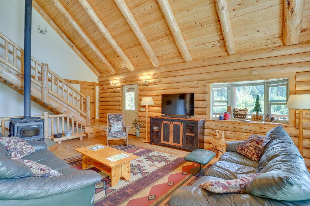 a living room with a couch and a television in a cabin at 13 Mi to Ski Slopes Log Home on 60 Private Acres! in McCloud