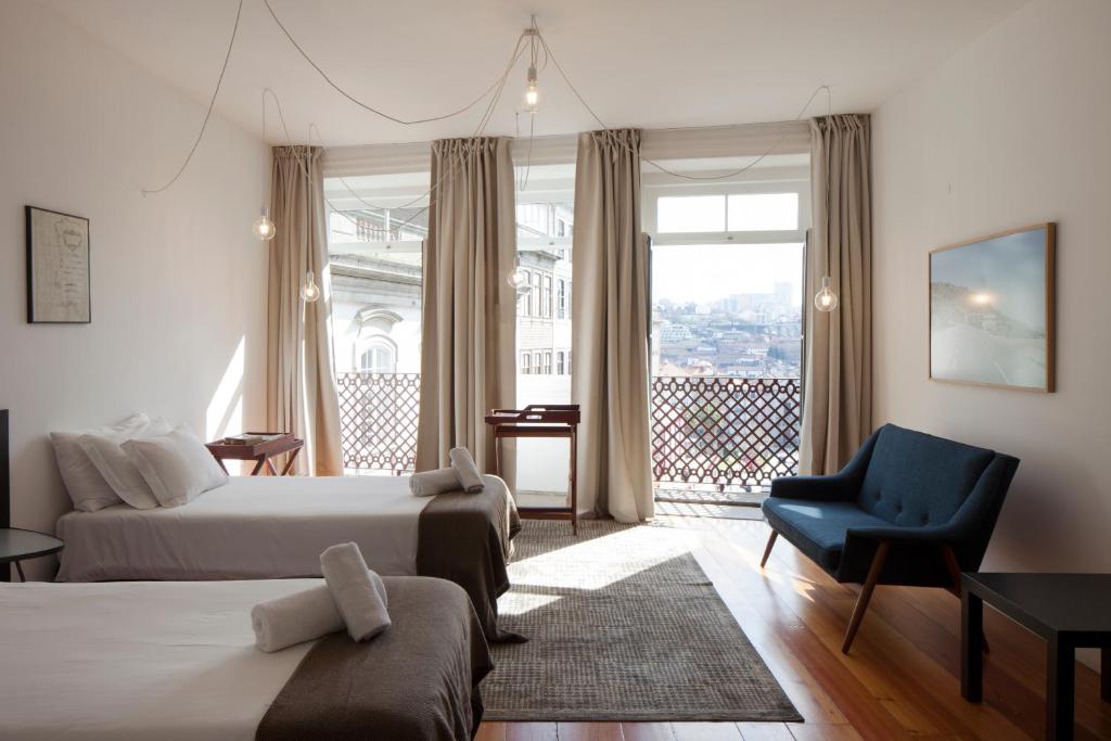 ein Hotelzimmer mit 2 Betten und einem blauen Stuhl in der Unterkunft Cale Guest House in Porto