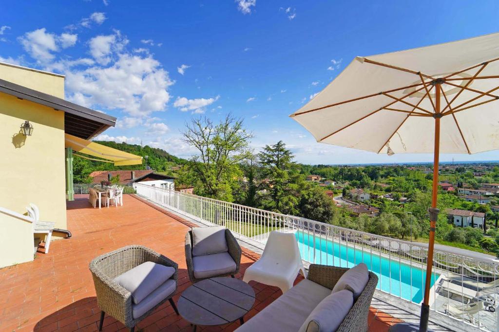 un patio avec un parasol et des chaises et une piscine dans l'établissement Villa Collina Del Sole 12 Pax by VILLASRETREATS, à Nicola