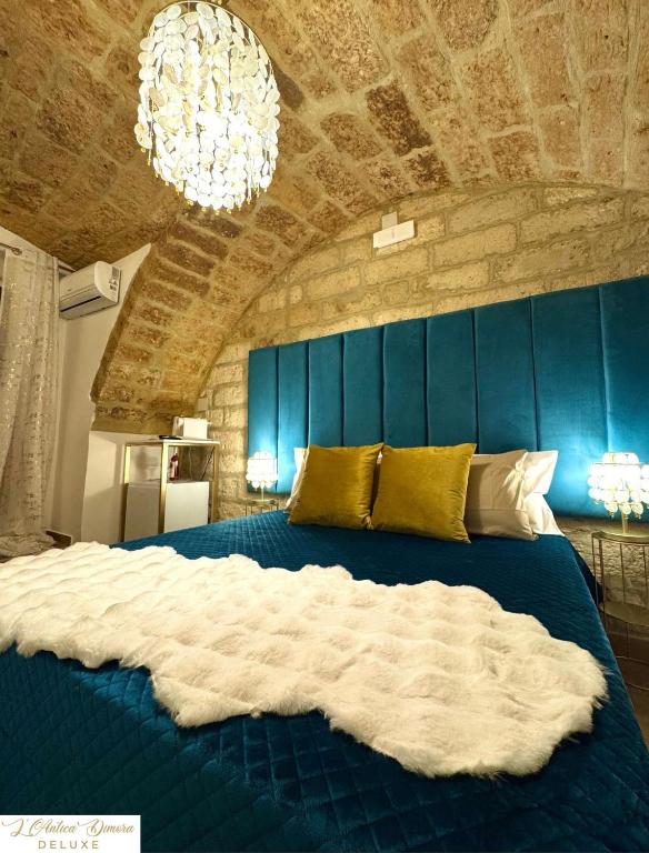 una camera da letto con un grande letto blu e un lampadario a braccio di L'Antica Dimora Deluxe a Bari
