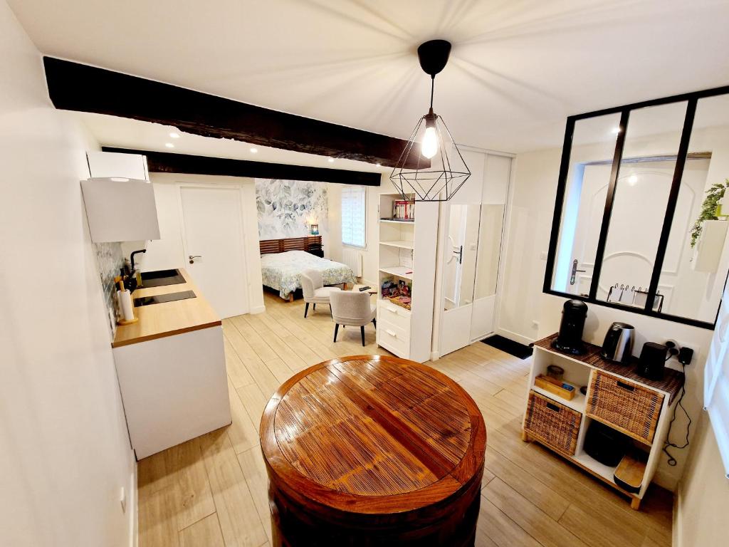 a living room with a table and a kitchen at Studio cosy Proche Lyon Arrivée autonome in Cailloux-sur-Fontaines