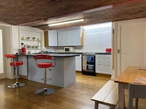 HenwickにあるPrivate city apartment, Upper Tything, Worcester City Centreのキッチン(白いキャビネット、赤いバースツール付)