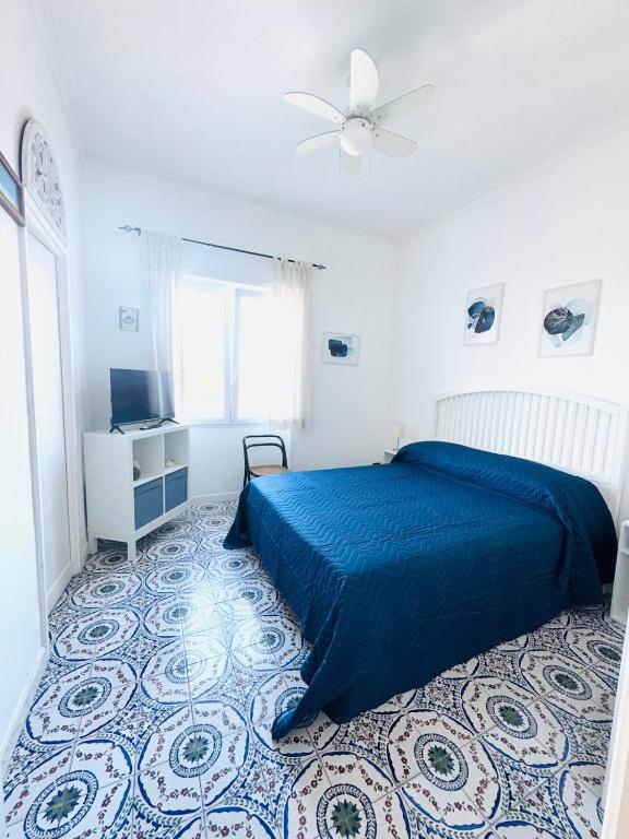 Un dormitorio con una cama azul y un ventilador de techo. en Eden Apartment, en Anacapri