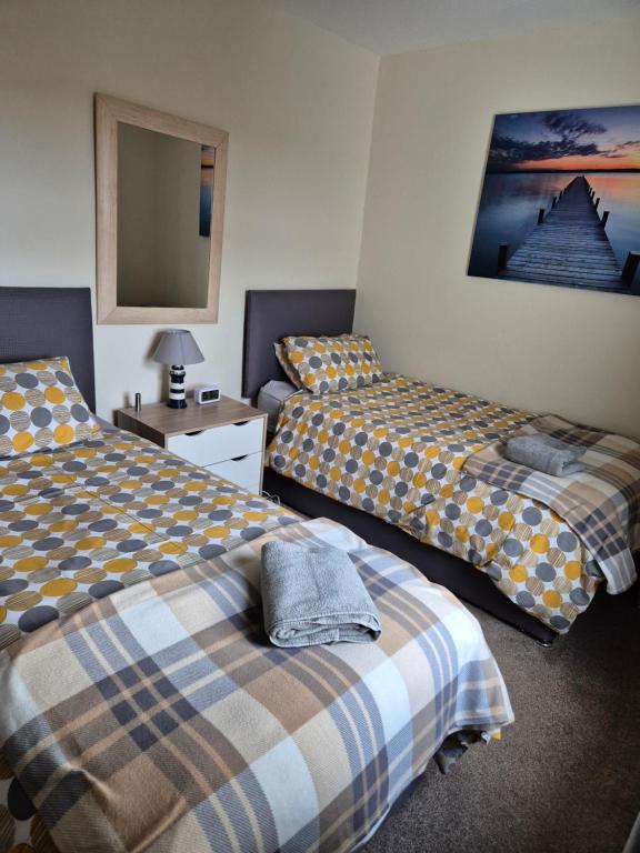 a bedroom with two beds and a mirror at RAWSON COTTAGE LOVELY 2 BEDROOM SEMI RURAL in Stranraer