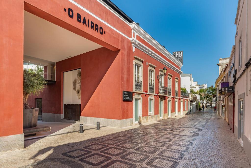 an empty street in a city with a red building at 3HB Faro in Faro