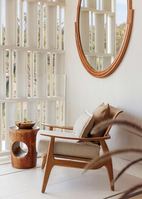 a living room with a chair and a mirror at One&Only Aesthesis, Athens in Athens