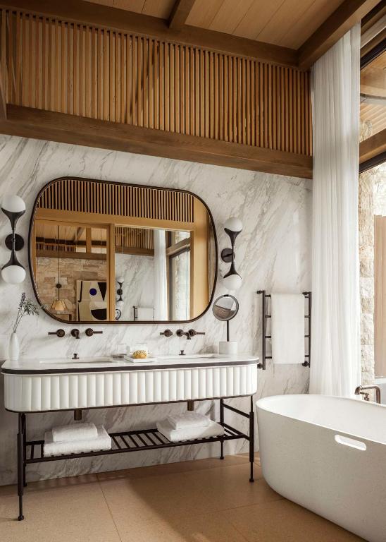 a bathroom with a tub and a large mirror at One&Only Aesthesis, Athens in Athens