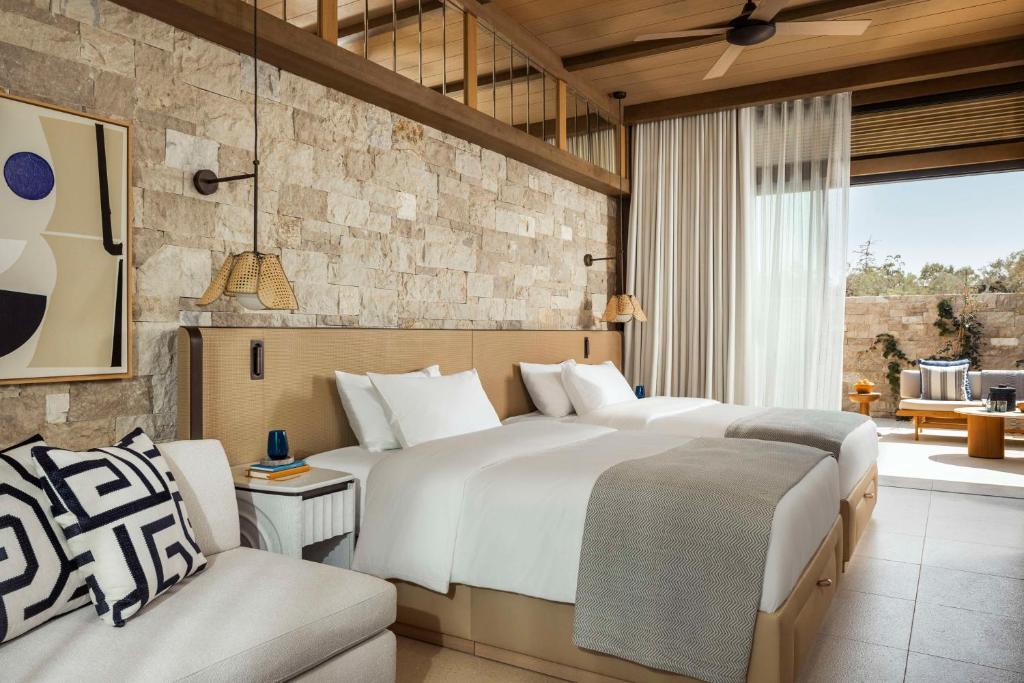 a bedroom with two beds and a stone wall at One&Only Aesthesis, Athens in Athens