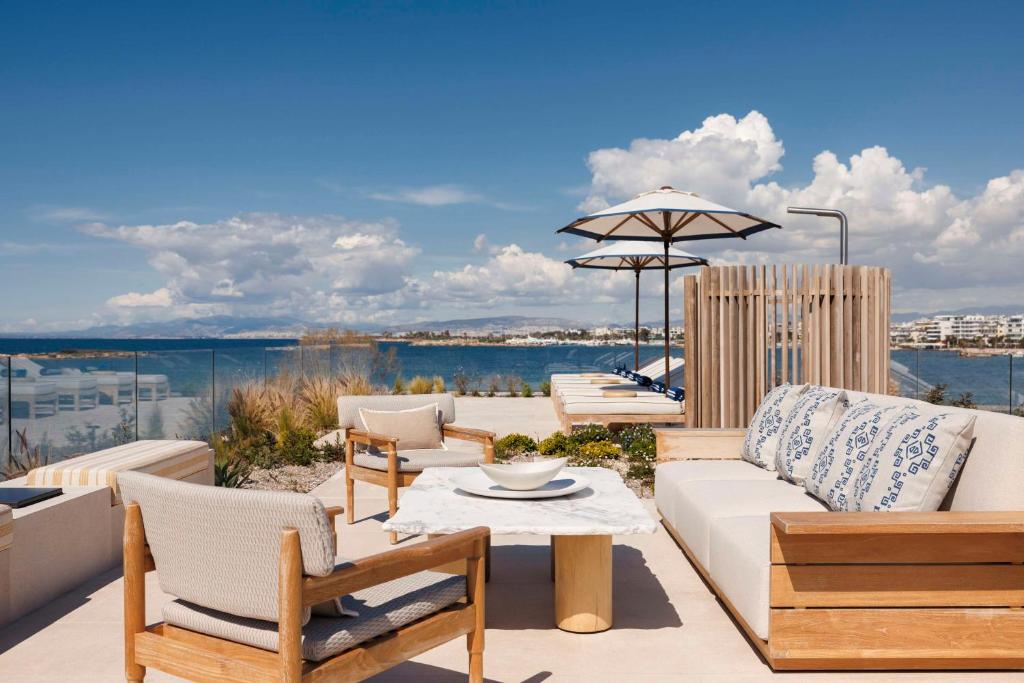a patio with chairs and a couch and an umbrella at One&Only Aesthesis, Athens in Athens