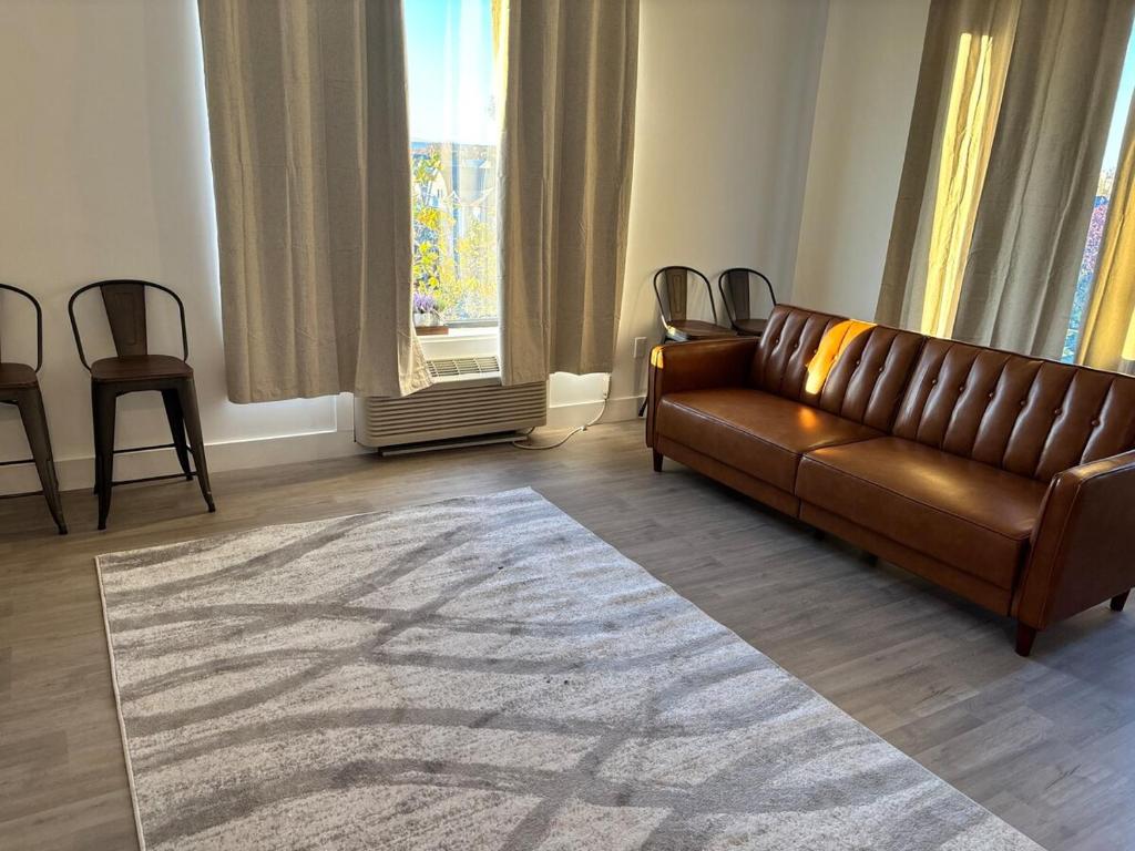a living room with a brown leather couch and a rug at Sweet getaway 6 min from EWR in Elizabeth