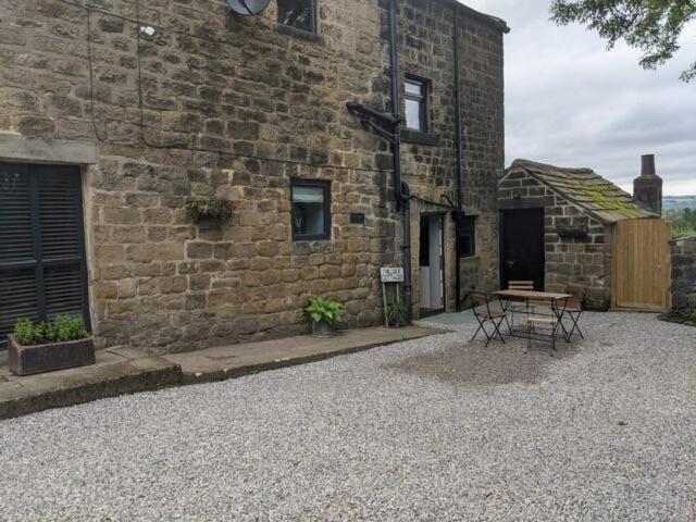 ein Steingebäude mit einem Tisch davor in der Unterkunft 1 Hillside Cottages in Leeds