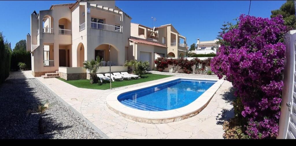 ein großes Haus mit einem davorliegenden Swimmingpool in der Unterkunft Villa Naomi in Les tres Cales