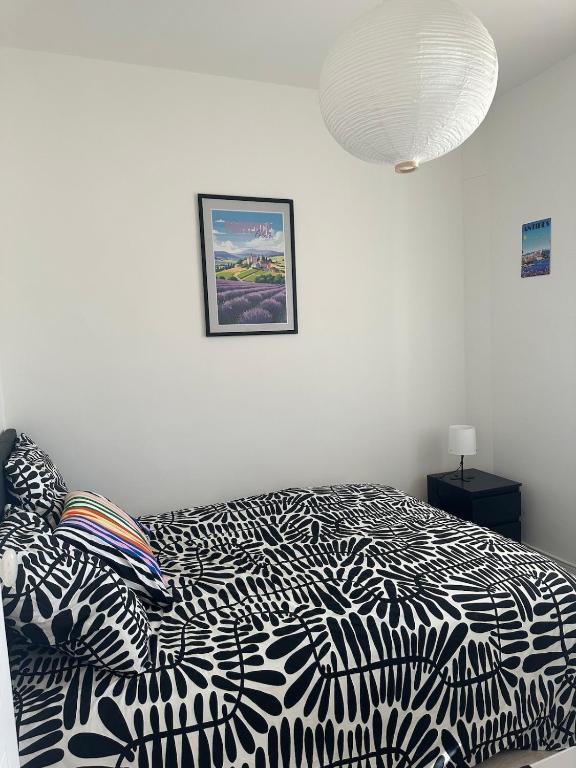 une chambre avec un lit avec une couette noire et blanche dans l'établissement Lumineux 2 pièces haut de villa, à Antibes