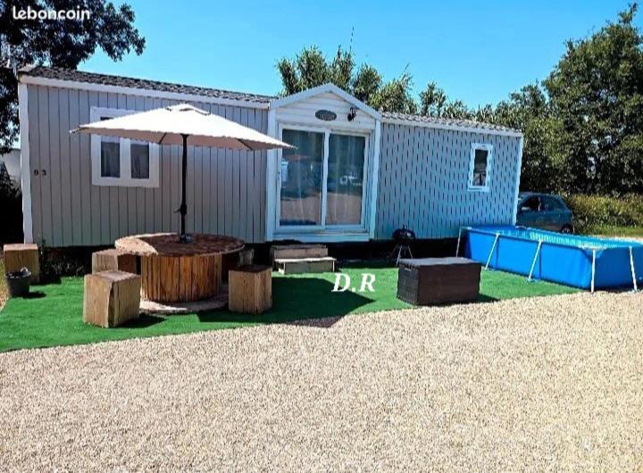 une caravane avec un parasol, une table et des bancs dans l'établissement Mobile Home de Charme 4 Personnes Sans Wifi, à Lançon-Provence