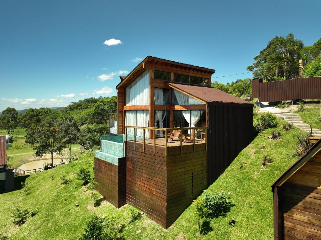 a house on top of a hill with grass at Vale Aurora Cabanas in Tijucas