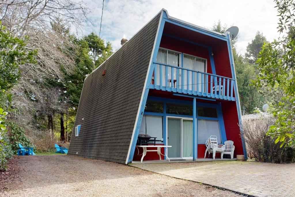 a small red house with a balcony and a table at The Sand Castle in Lincoln Beach