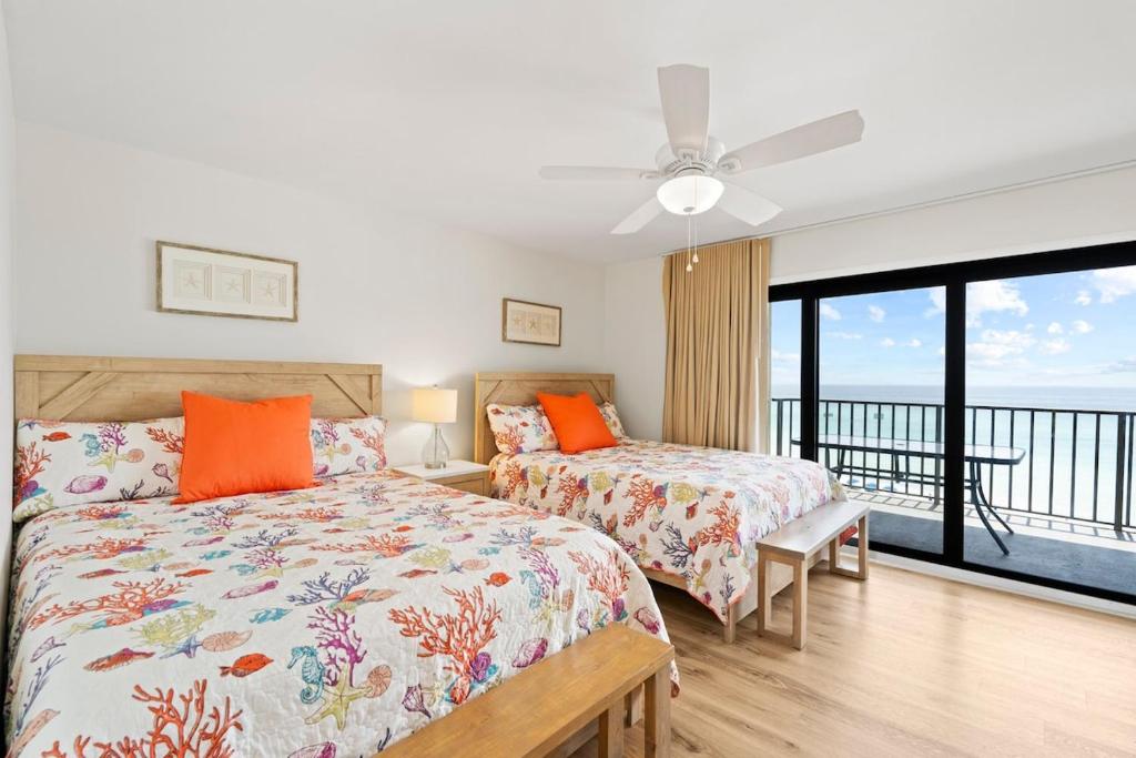 a bedroom with two beds and a balcony at Commodore 606 3 BR 3 BA Sleeps 12 in Panama City Beach