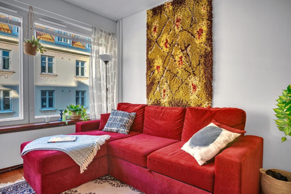 un canapé rouge dans un salon avec une fenêtre dans l'établissement Design District w Free Parking Garage, Balcony, Netflix, 200m tram&bus, à Helsinki