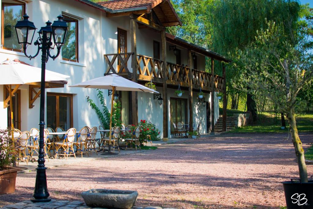 - un bâtiment avec des tables, des chaises et un parasol dans l'établissement La Ferme aux Biches, à Commelle-Vernay