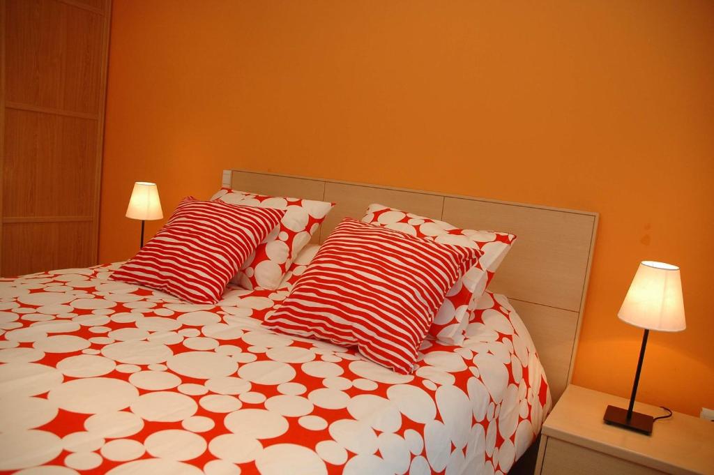 1 dormitorio con 1 cama con almohadas rojas y blancas en Apartamentos Costa Costa, en Suances