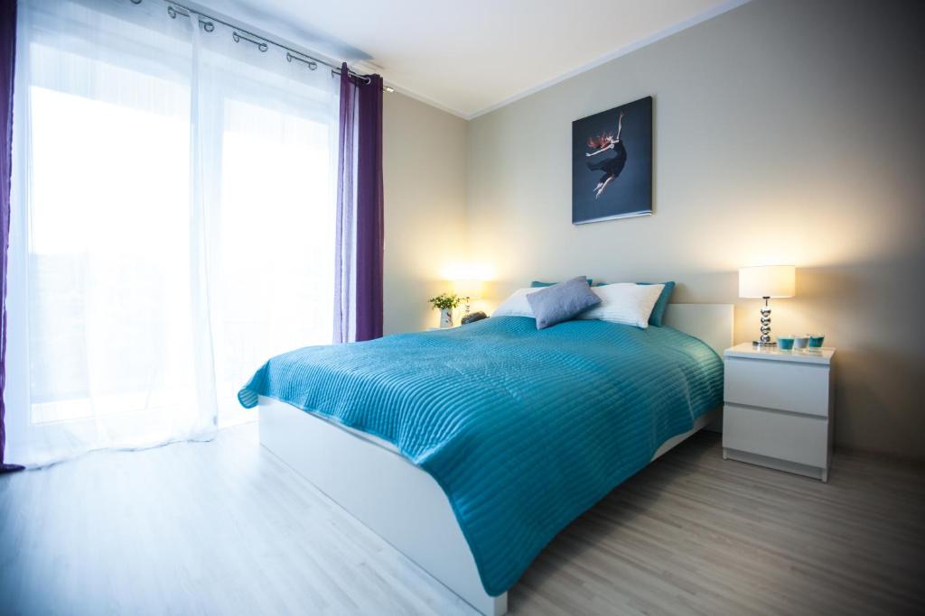 1 dormitorio con cama azul y ventana grande en Apartamenty Feniks & Pegaz, en Świnoujście