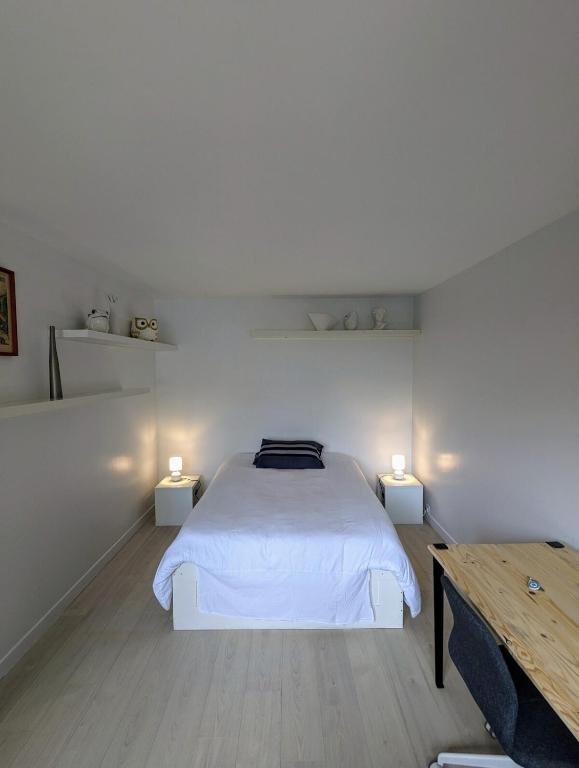 - une chambre blanche avec un lit et deux lumières dans l'établissement Studio cosy, refait à neuf, à Paris