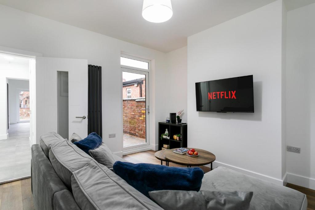 a living room with a couch and a tv on a wall at The Modern Retreat in Leicester