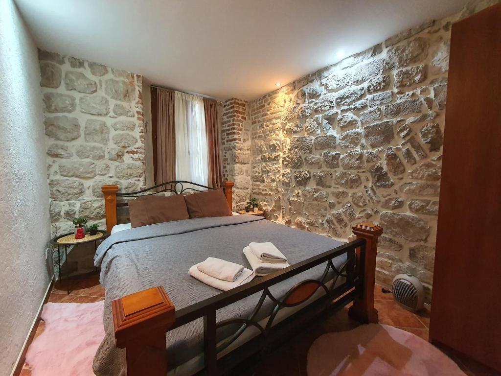 une chambre avec un lit et un mur en pierre dans l'établissement Little Bay Apartments, à Kotor