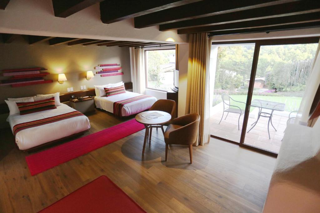 a bedroom with two beds and a living room with a patio at Hotel Avandaro Golf & Spa Resort in Valle de Bravo