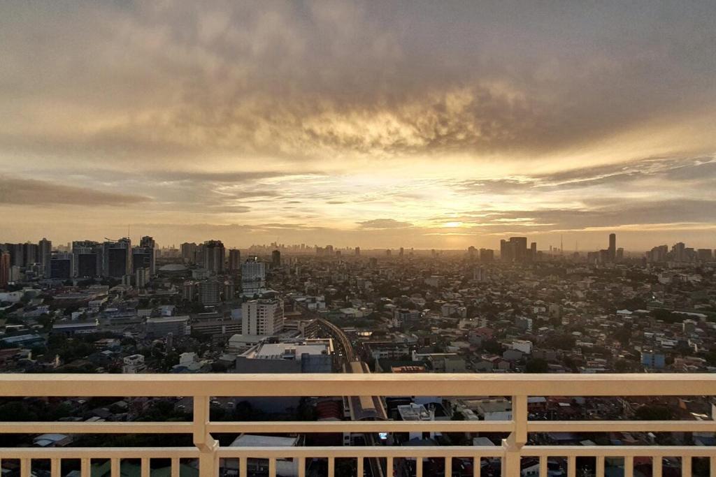 a view of a city at sunset from a balcony at Modern and Cozy 2-Bedroom Condo in Prime Location in Manila