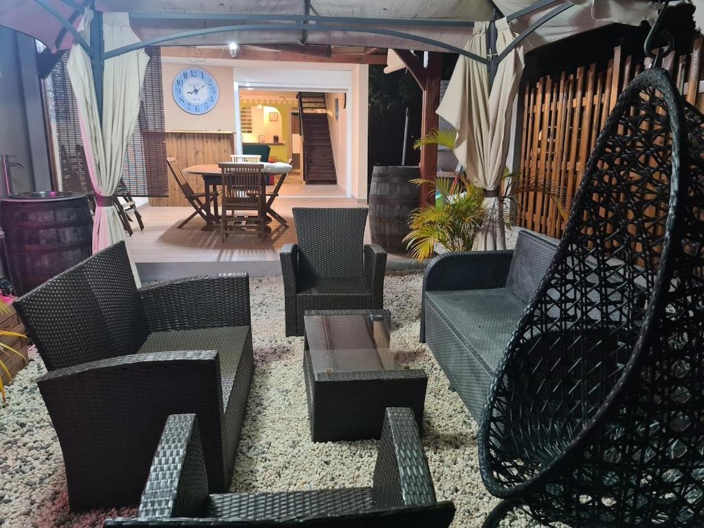 un patio con sedie, tavoli e un ombrellone di Villa Kasanaco avec vue sur la mer a Case-Pilote