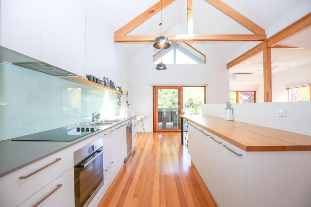 a kitchen with white cabinets and a wooden floor at The Stelvio Villas - One in Bright