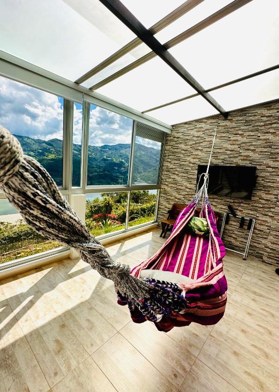 a hammock hanging in a room with windows at La Vista EcoHouse in Macanal